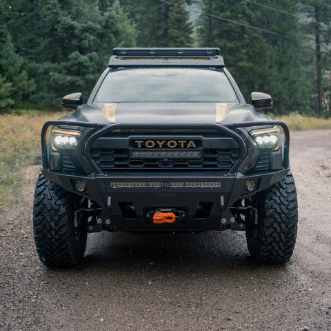 White Toyota Tacoma equipped with a C4 Overland bumper with full height bull bar and headlight hoops with a lazy dog in the foreground.
