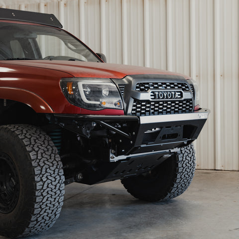 Quartering view of a red Tacoma with the Rock Runner front bumper installed and the RR front skid with crossmember delete.