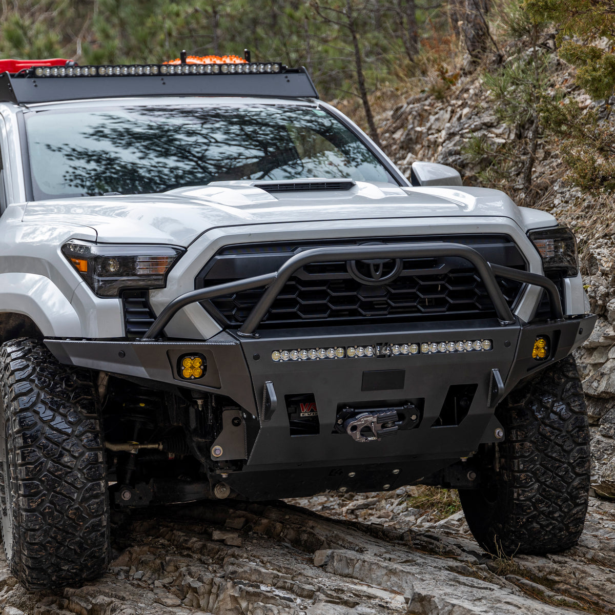 2024 Tacoma offroading in the mountains and equipped with a C4 Overland Series winch bumper with led light bar, fog lights and winch installed.