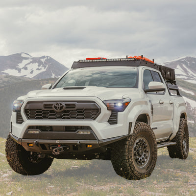 White Tacoma in the spring-time mountains equipped with the C4 Lo-Pro front winch bumper.