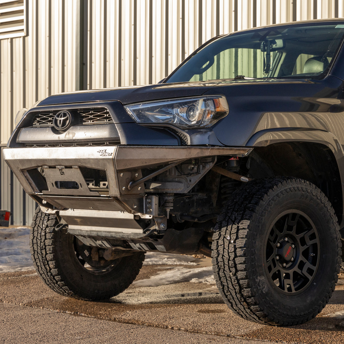 Low angle view of a grey Toyota 4Runner with the C4 Rock Runner winch bumper installed with plate-style side wings.