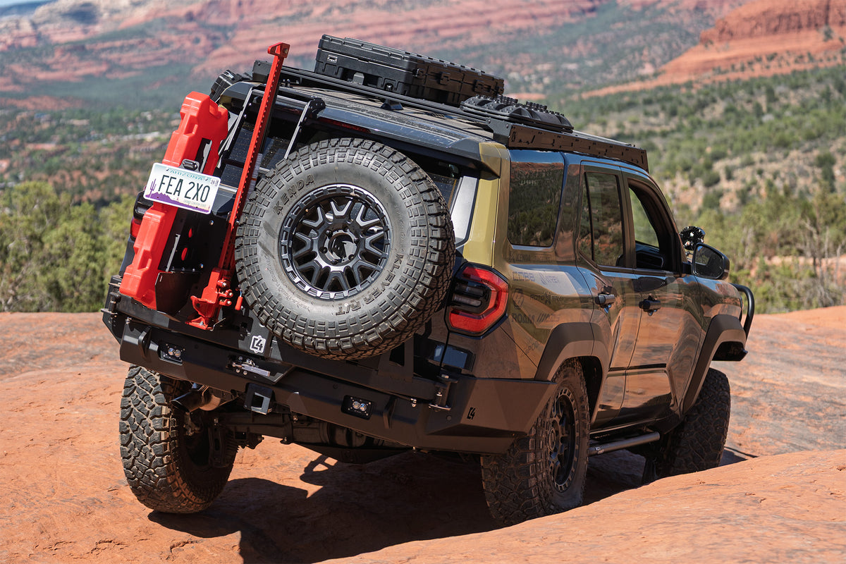 Our 4Runner with C4 black roof rack and rear bumper, carrying a spare tire, red fuel canisters, and a black roof box, shown climbing a red rock desert trail in Sedona.