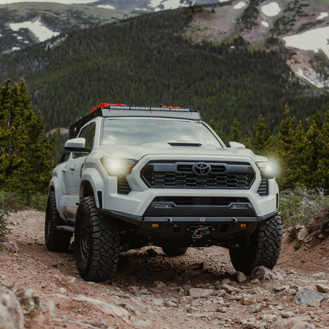 White 2024 Tacoma navigating a mountain road while equipped with the C4 Lo-Pro front winch bumper.