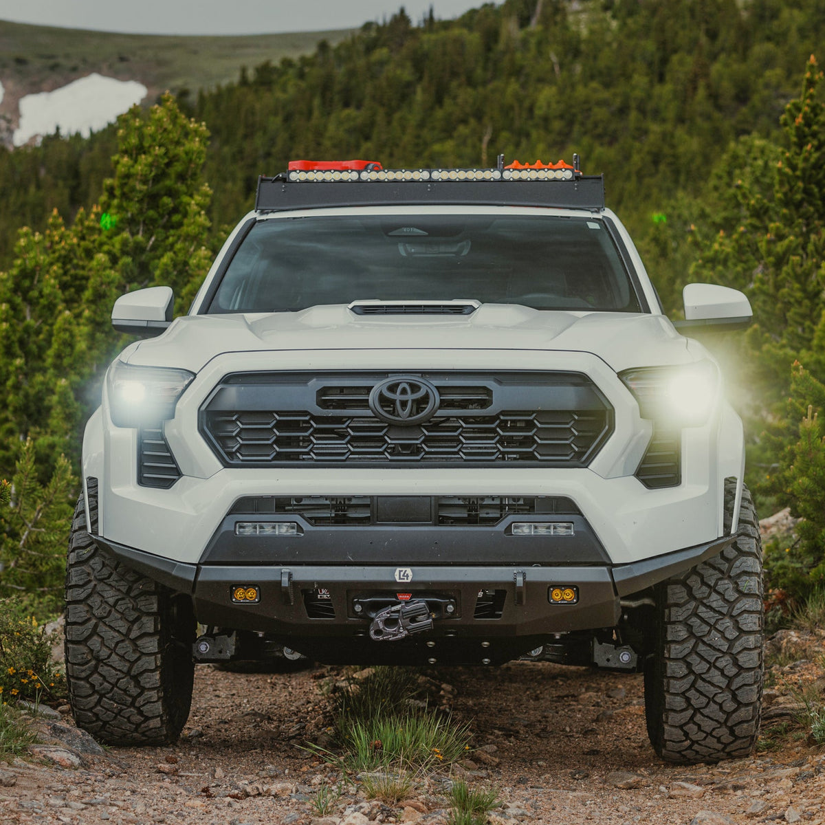 Front shot showing the C4 Lo-Pro bumper on a white Tacoma with the additional High Clearance Side Additions installed.