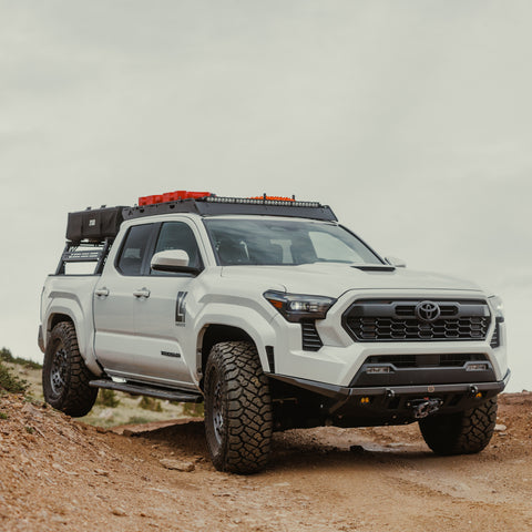 White 2024 Tacoma on a dirt road equipped with the affordable C4 Lo-Pro front winch bumper.