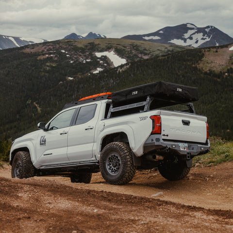 Rear view of a white Tacoma exploring the mountains and well-equipped with overlanding gear and accessories.
