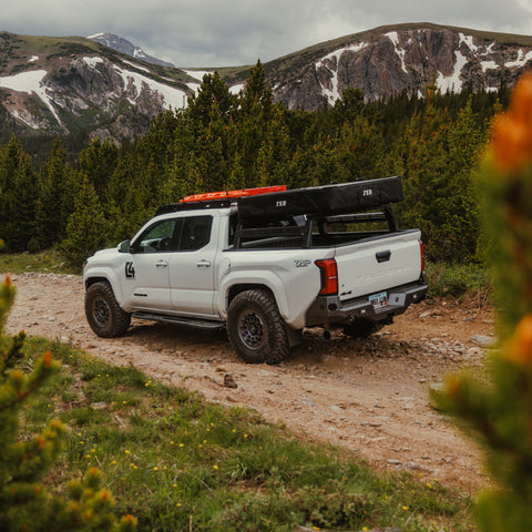 White Tacoma in the mountains with a C4 Overland rear bumper equipped. 