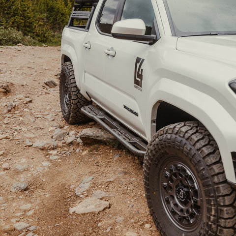 Quartering front view of the C4 Sliders for 2024 Tacomas showing how much the sliders and steps protrude from the vehicle providing both protection and a solid, wide surface to step on to enter the vehicle. 