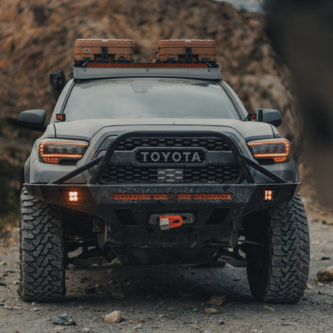 Grey Tacoma on a mountain road with a winch bumper.