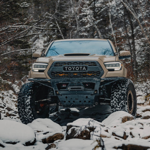 Tan 3rd Gen Tacoma offroading in the snow and equipped with the C4 Rock Runner front winch bumper.