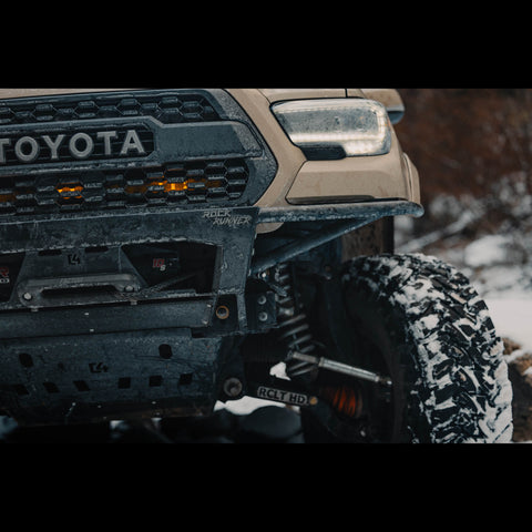 Close-up view of the Rock Runner bumper with the RCLT HD long travel rock crawling long travel system on a tan Tacoma. 