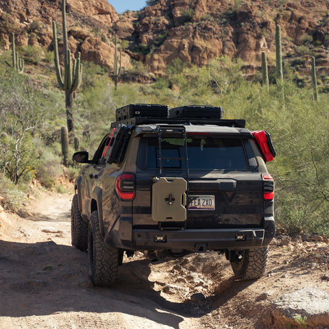 The C4 4Runner build navigates washed out desert trail, equipped with bumpers, roof rack, ladder, and MOLLE panels.