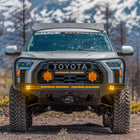 White Toyota Tundra on a dirt road with snow-capped mountains in the background and a C4 Overland front bumper prominently featured on its front end.