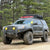 Black 4th Generation 4Runner on a muddy mountain road fully equipped for overland travel to include a lift and oversized tires, a roof rack with MaxTrax, a rooftop tent, auxiliary lighting, winch and a steel bumper from C4 Fabrications.