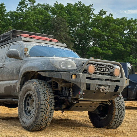 Low-angle shot of the C4 Overland winch bumper for the Toyota 4Runner equipped on a black 2006-2009 model along with roof rack, roof top tent, recovery boards, winch and auxiliary lighting.