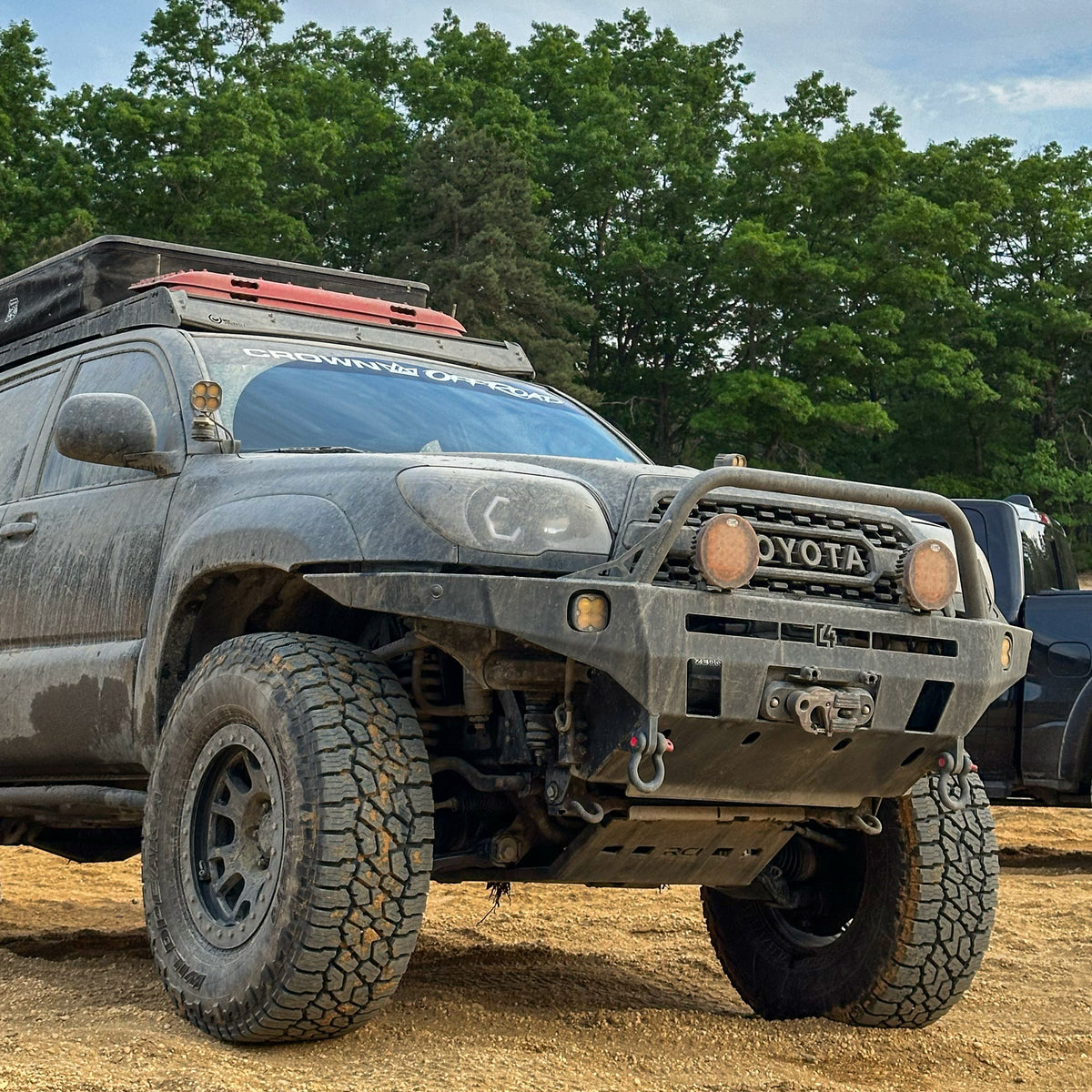 Low-angle shot of the C4 Overland winch bumper for the Toyota 4Runner equipped on a black 2006-2009 model along with roof rack, roof top tent, recovery boards, winch and auxiliary lighting.