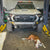 White Toyota Tacoma equipped with a C4 Overland bumper with full height bull bar and headlight hoops with a lazy dog in the foreground.