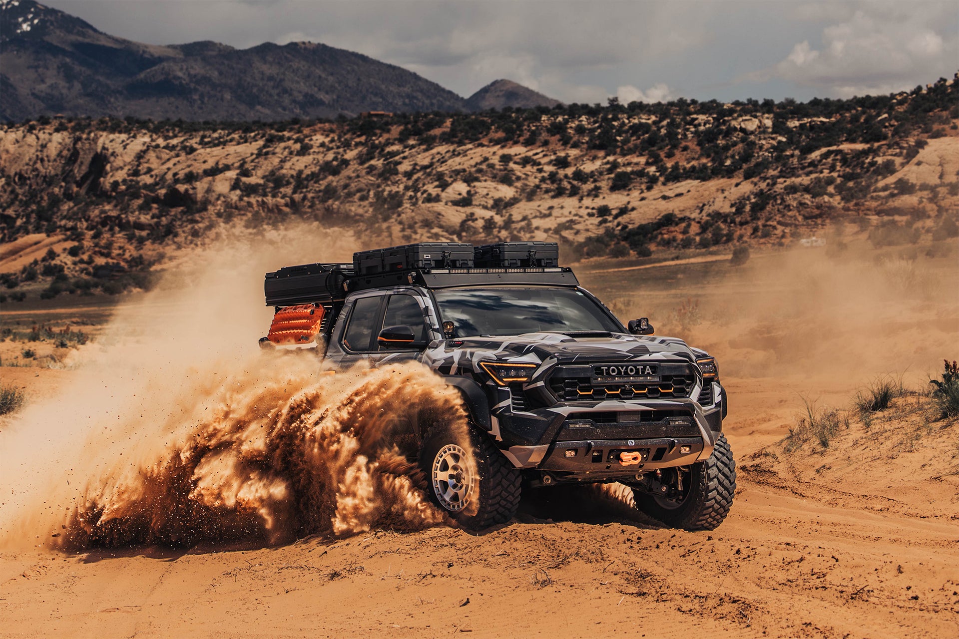 4th Gen Tacoma blasting through fine dirt with cloud of dust forming. Equipped with C4 Bumpers.