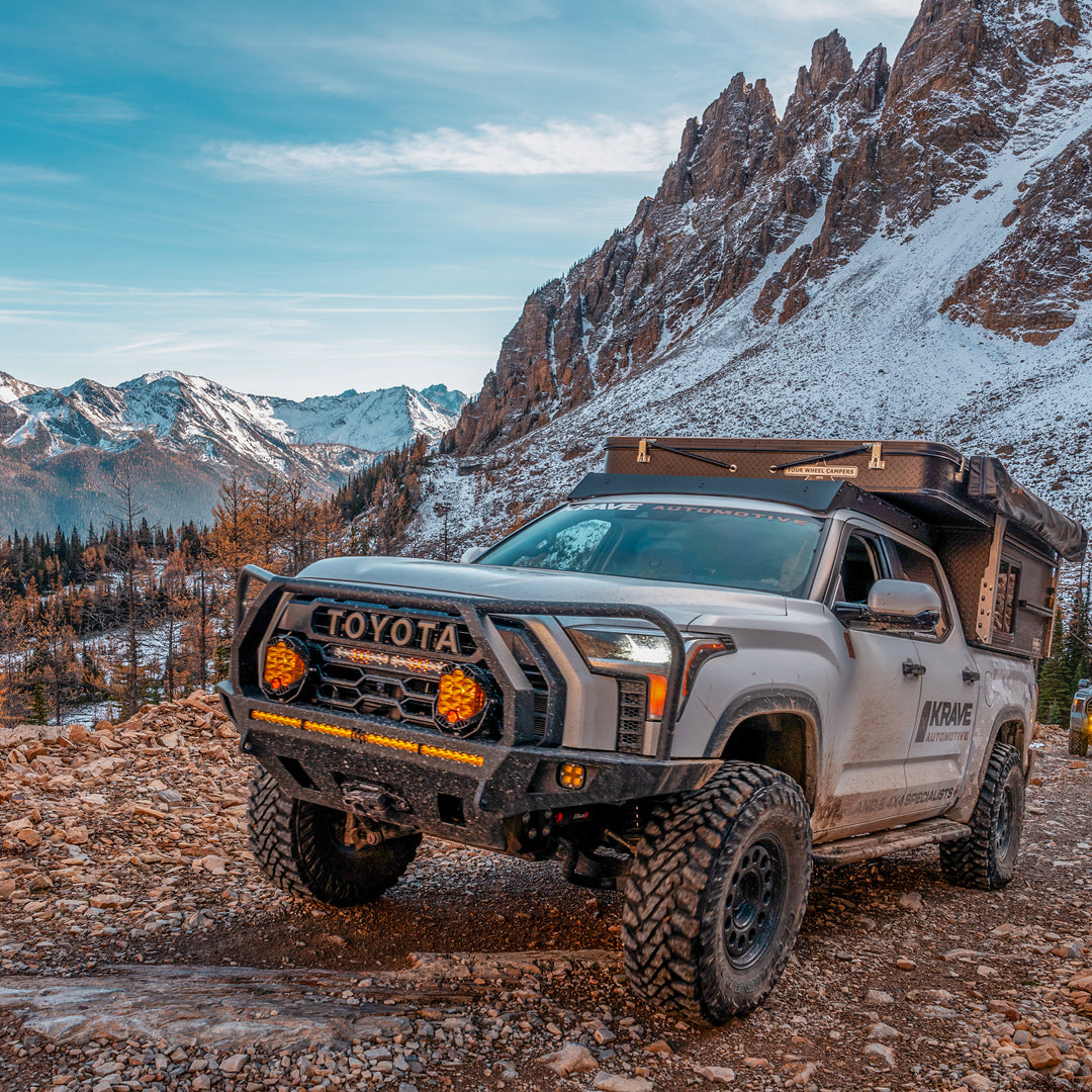 White 3rd Gen Tundra wheeling in the mountains with emphasis on the C4 Fabrication Overland winch bumper with full-height bull bar and headlight hoops. 