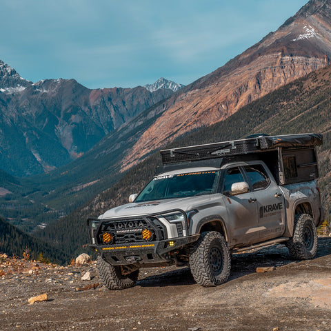 White 2022+ Tundra with lift, tires, C4 armor and pop-top topper camper.