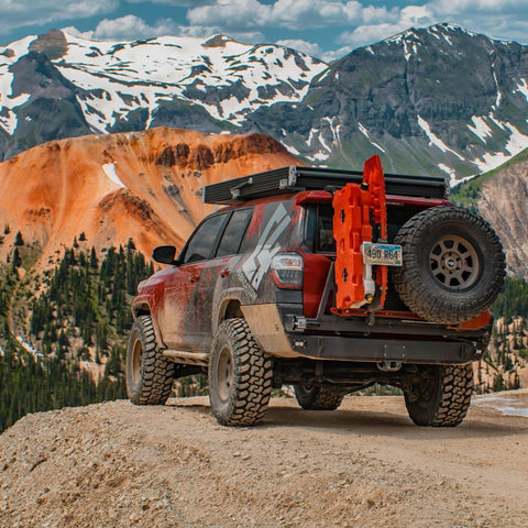Maroon 4Runner at a mountain overlook with a rooftop tent, sliders and the Overland Rear Bumper with full-width single swing from C4 Fabrications.