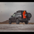 Black 4Runner on a beach equipped with the C4 fabricated steel rear bumper with dual swing-outs holding a spare tire on the passenger side and RotoPax, MaxTrax and a high-lift jack on the driver's side.