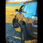 Look down the side of a grey 4Runner overlooking a lake, showing the kick-out at the rear of the C4 Rock Sliders.