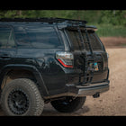 Driver's rear quartering shot showing a black 4Runner with the C4 Summit hatch ladder. 