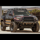 Wide-body Tacoma with purple wrap and a C4 Hybrid bumper.
