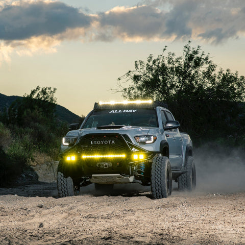 Blue Tacoma running high speed down a sand road at sunset with a C4 Hybrid front bumper with full-height bull bar.