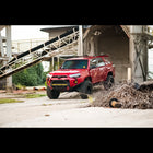 Red 4Runner parked in an industrial lot equipped with C4 Lo-Pro bumper and High Clearance Additions.