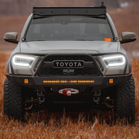 Straight on view of a Tan Tacoma with a roof rack and C4 Overland front winch bumper.