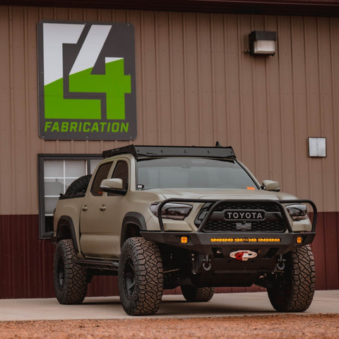 Tan Tacoma parked outside of the C4 facility and equipped with a three-hoop winch bumper.