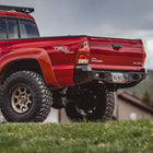 Low angle quartering view of the C4 Overland rear bumper on a red Tacoma.