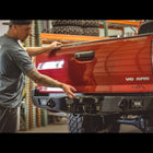 C4 owner Caleb Rupp demonstrating the hidden hitch on the C4 Overland rear bumper by pivoting up the license plate to reveal the receiver. 