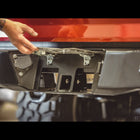 Close up view of the hidden hitch underneath the hinged and spring-loaded license plate frame on the C4 Overland rear bumper for the 2nd Gen Tacoma.