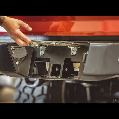Close up view of the hidden hitch underneath the hinged and spring-loaded license plate frame on the C4 Overland rear bumper for the 2nd Gen Tacoma.