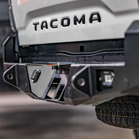 Quartering side view of the hidden hitch receiver concealed under the license plate mount on the C4 Overland rear bumper.