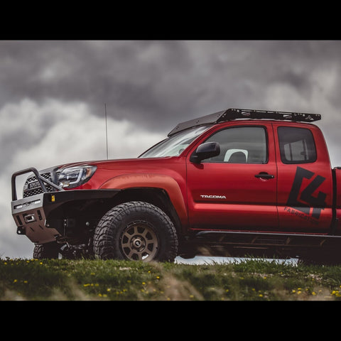 Low-angle side view from a distance of a red extended cab 2nd Generation Tacoma with the C4 Overland winch bumper installed.