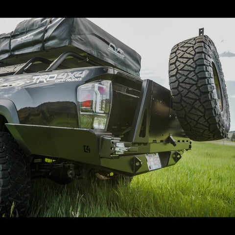Close-up view of the latch side of the C4 high clearance rear bumper with tire swing out installed on a black Tacoma.
