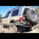 Tan four door Tacoma with a pop-top topper and the C4 High Clearance Rear Bumper.