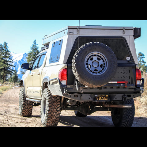 Tan Tacoma with pop-top topper and C4 rear swing-out bumper.