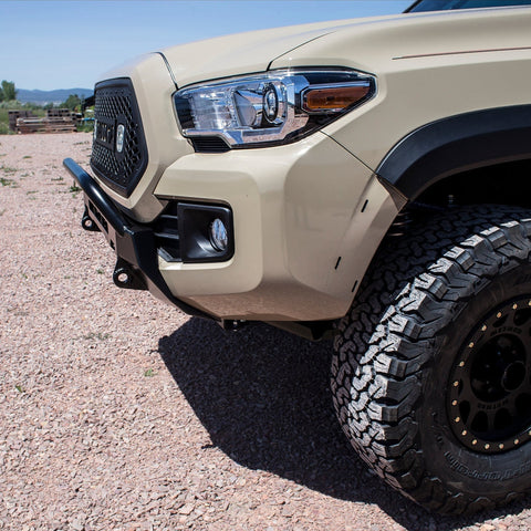 Low profile winch bumper incorporated into the front plastic bumper of a tan Tacoma.