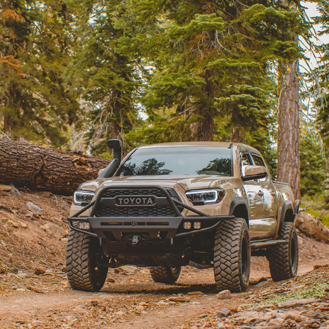 Tan 3rd Gen Tacoma on a mountain dirt road equipped with a snorkel and C4 Hybrid bumper and Sliders.