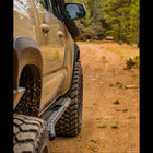 Tacoma on a dirt trail in the mountains sporting a set of C4 Sliders to protect it from rock damage.