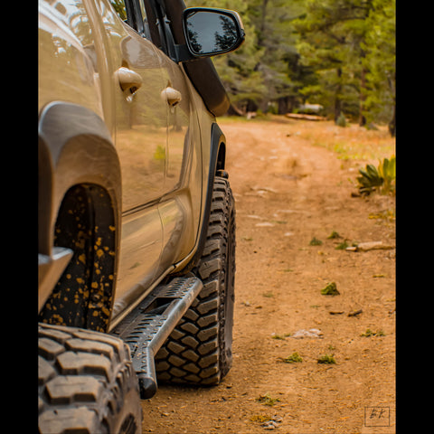 Tacoma on a dirt trail in the mountains sporting a set of C4 Sliders to protect it from rock damage.