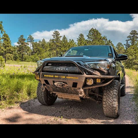 The muddy front end of a 2014+ 4Runner while offroading and equipped with a C4 Hybrid winch bumper. 
