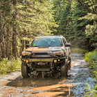 Action photo of a 2014+ 4Runner splashing through a wet and muddy mountain trail and equipped with a C4 Hybrid winch bumper.