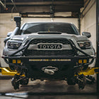 Tacoma on lift with the wheels off and equipped with a Hybrid bumper from C4 Fabrication.