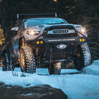 Tacoma off-roading in the snow and equipped with a pop-top topper and C4 Hybrid front bumper.
